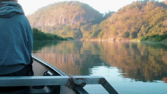 View of a person in a boat on the river with lush hills in the background in Kecamatan Kambera, Nusa Tenggara Timur, Indonesia.
