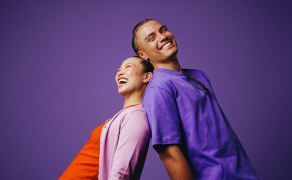 Portrait of friends shows them smiling together on a purple background
