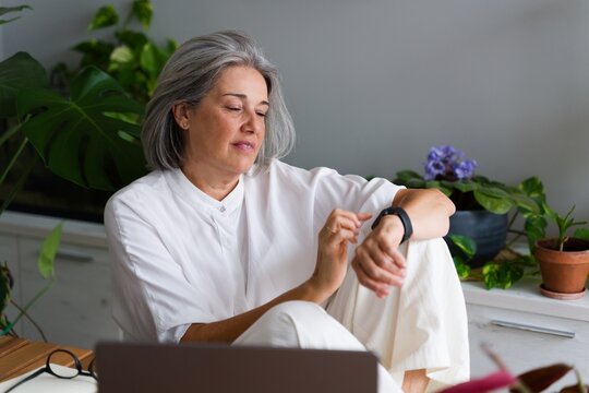 Middle-aged white woman checking wrist device indoors