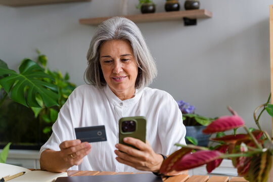 Mature white woman completing an online payment via smartphone