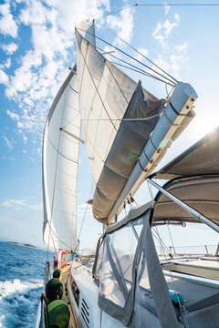 View from deck of sailing yacht with fully deployed sails cruising across Adriatic Sea under bright blue sky. Dynamic maritime travel scene representing freedom, adventure and nautical lifestyle