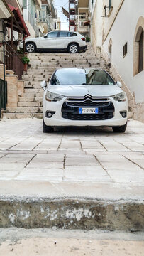 White Citro&euml;n DS4 in front of a steep stepped alley with a parked BMW X1 in the background; tight parking in the old town of Peschici, Province of Foggia, Gargano, Puglia, Italy 28.11.2025