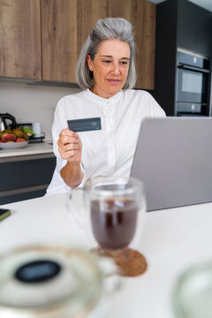 Senior white woman using laptop and credit card for online shopping