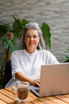 White Woman working on laptop indoors at home office with coffee