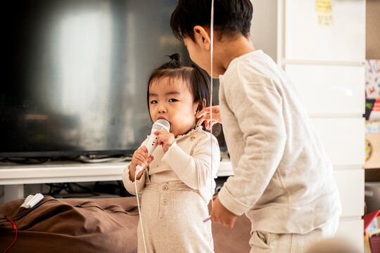 Cute Asian Toddler Baby Girl Looking Up at Her Older Brother at Home