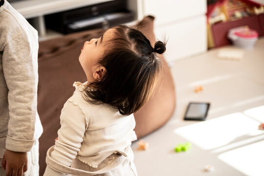 Cute Asian Toddler Baby Girl Looking Up at Her Older Brother at Home