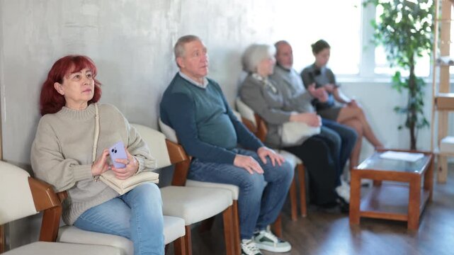 Quiet elderly people sitting in clinic waiting area before doctor consultation. High quality 4k footage