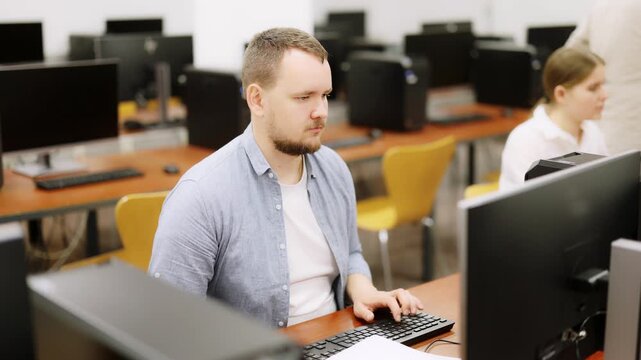 Man student of computer courses types on keyboard, performs work, educational practical task. Pupil performs educational tasks using computer 