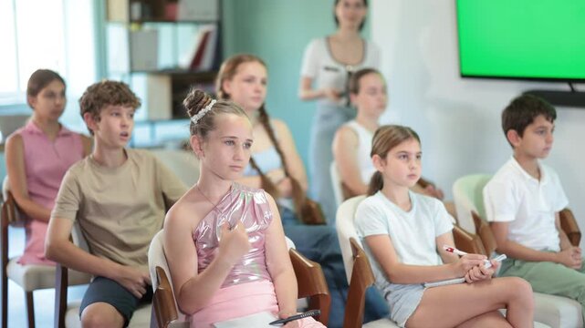 Focused preteen and teenage students attending interesting educational lecture at training seminar room 