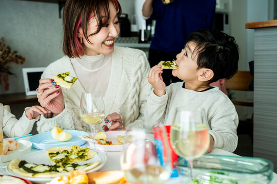 Asian Mother and Son Eating Pizza and Smiling Together at Home Dining Table