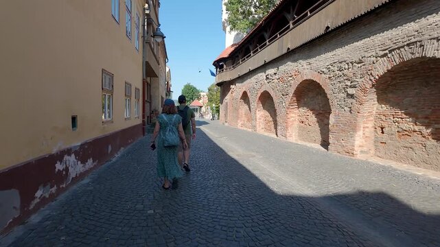 Pedestrians walking beside medieval fortification wall on Cetatii Street in old town Sibiu Romania