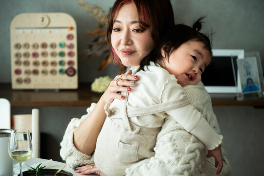 Asian Mother Holding Baby Girl on Shoulder with Love Indoors at Home