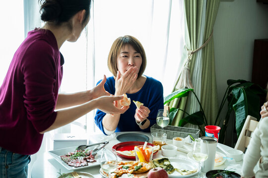 Asian Friends Enjoying Food and Talk around Home Dining Table at Party