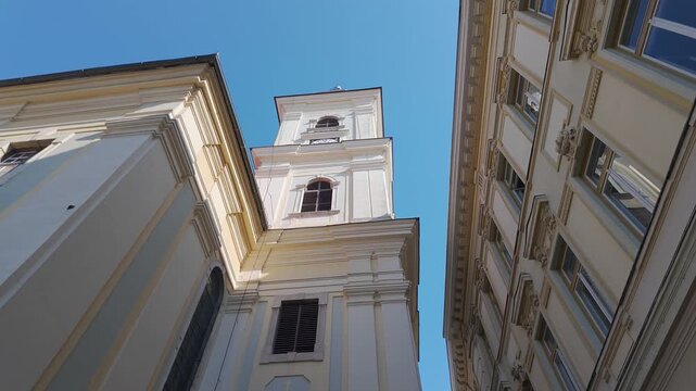 Low angle view of Holy Trinity Roman Catholic Church tower between historic buildings in Sibiu Romania