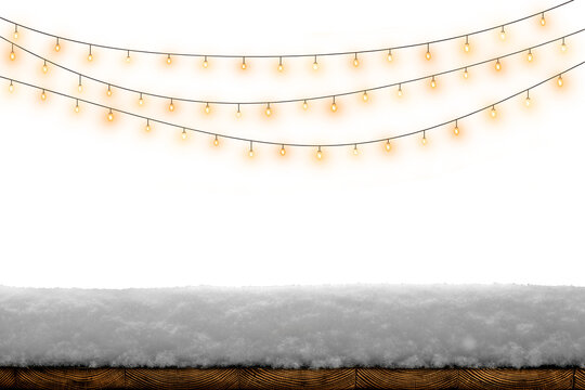 Warm glowing string lights above snow on a rustic wooden board, creating a cozy winter holiday background.