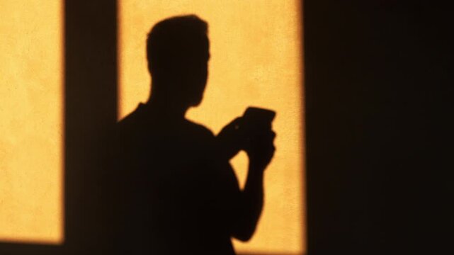 Shadow silhouette of a person using a mobile phone to socialize