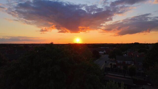 aerial sunset being reveled behind tree over a English suburb