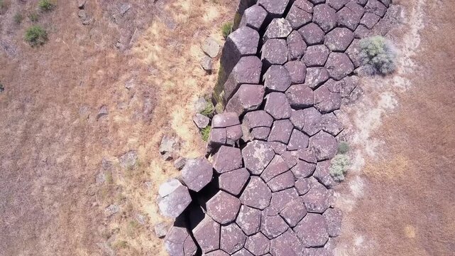 Aerial view of hexagonal basalt columns forming natural volcanic patterns in high desert terrain.