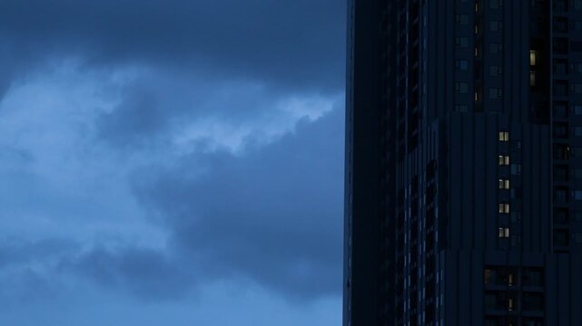 High-Rise Condominium Silhouette Against Moody Blue Cloudy Sky Before Rain, Dusk Cityscape
