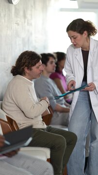 European man standing in the reception area after an interview and chatting with a woman nurse to get a medical record before applying for a job . High quality 4k footage