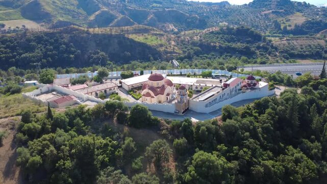 Aerial shot of a historic monastery surrounded by trees and mountains