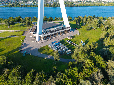 Aerial view of the Riga Radio and TV Tower base with surrounding data center infrastructure, green parkland, and the Daugava River in the background in Riga, Latvia.