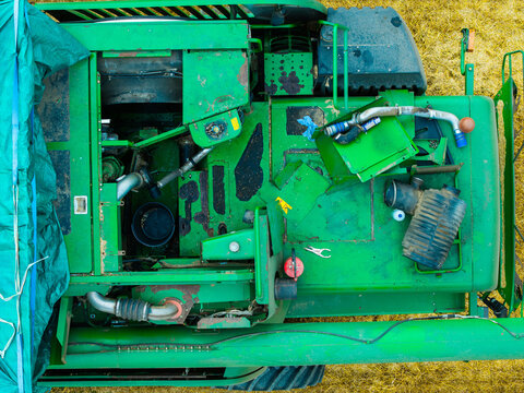 Aerial view of a broken-down green combine harvester abandoned in a field with mechanical parts exposed under an overcast sky in Jaunberzes pagasts, Dobeles novads, Latvia.