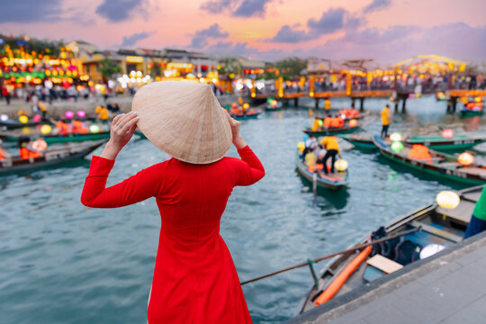Young asian woman in red dress overlooking lantern boats in hoi an at sunset