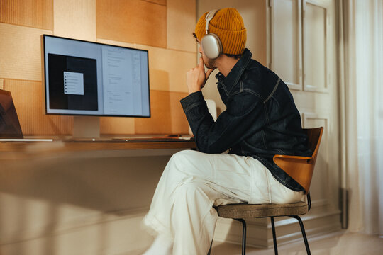 Focused work happens at a computer desk with headphones in a home office