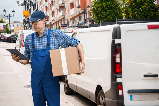 Delivery man in uniform with digital tablet and box