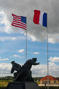 American and French flags flying beside a war memorial statue at Utah Beach Normandy France