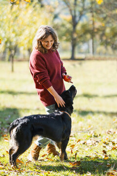 Woman playing with her dog in an autumn park