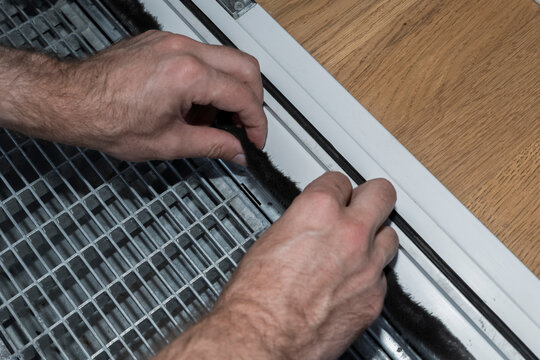Installing weather stripping seal on a window frame illustrates precise installation work for improved insulation efficiency.