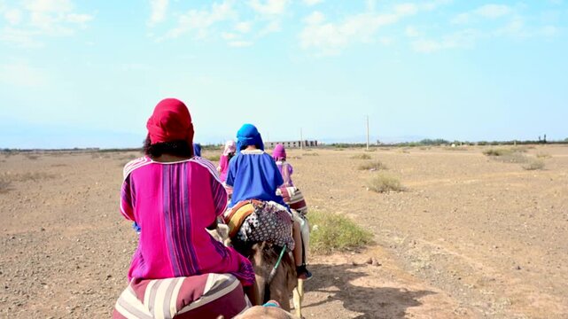 Marrakech, morocco. August 9, 2026. Tourists in traditional attire riding a camel caravan through the arid landscape of marrakech, morocco. An authentic desert adventure