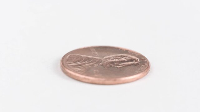 Single united states copper penny rotating on white surface.