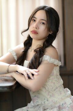 Elegant young woman with long braided hair and contemplative expression indoors