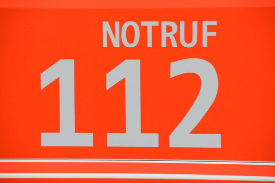 Aufschrift "Notruf 112" f&uuml;r Feuerwehr auf neonrotem Fahrzeughintergrund