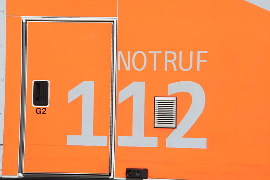 Aufschrift "Notruf 112" f&uuml;r Feuerwehr auf neonrotem Fahrzeughintergrund
