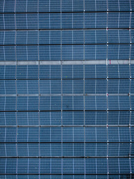 Aerial view of solar panels on a rooftop during a rainy day, highlighting the challenges of renewable energy generation in Riga, Latvia.
