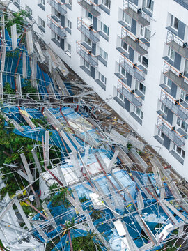 Aerial view of collapsed scaffolding and blue protective netting at a residential apartment building renovation site in Riga, Latvia.