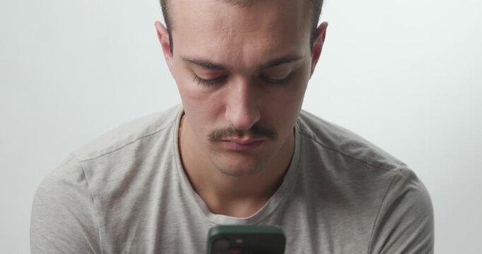 Close-up of Young Man Focused and Typing on Smartphone in Studio