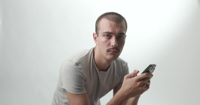 Young Man in Profile Using Smartphone and Turning to Look at Camera