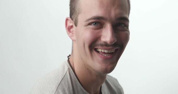Close-up of Happy Young Man Turning and Laughing at Camera on White Background