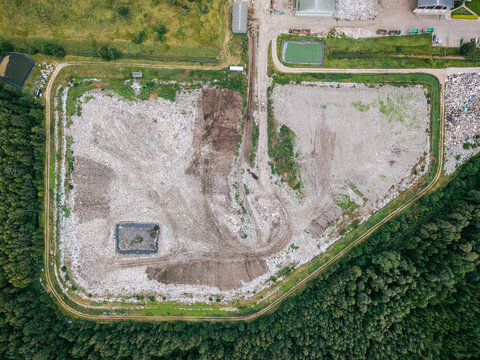 Aerial view of a municipal solid waste landfill with waste processing areas, sorting zones, and surrounding forest landscape in Laidzes pagasts, Talsu novads, Latvia.