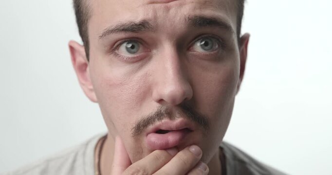 Extreme Close-up of Pensive Young Man Touching Chin and Thinking on White Background
