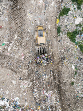Aerial view of a yellow bulldozer pushing waste at a municipal solid waste landfill in Laidzes pagasts, Talsu novads, Latvia.