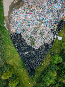 Aerial view of a large landfill site filled with discarded tires and mixed waste, surrounded by green grass and trees in Laidzes pagasts, Talsu novads, Latvia.