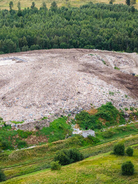 Aerial view of a municipal solid waste landfill with piles of processed refuse and surrounding green forest in Laidzes pagasts, Talsu novads, Latvia.