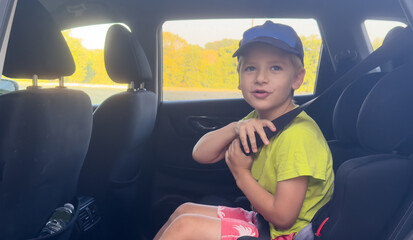 Naklejka premium child sitting in car seat with seatbelt, bright yellow shirt, family travel, casual, front seat perspective, inside vehicle, fabric, plastic, black, yellow, green, pink, water bottle, clean.