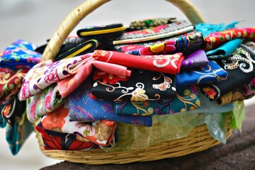 Naklejka premium Authentic, artisan, handmade traditional silk scarves in a wicker basket sold on the cobblestone streets of San Miguel de Allende in Mexico.